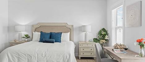 Un dormitorio con cama, mesitas de noche, un escritorio y una silla.