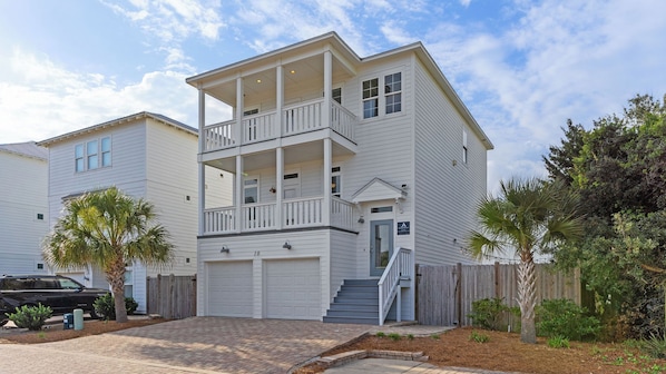 A two-story residential building with a balcony, a garage, and a staircase leading to the second floor.