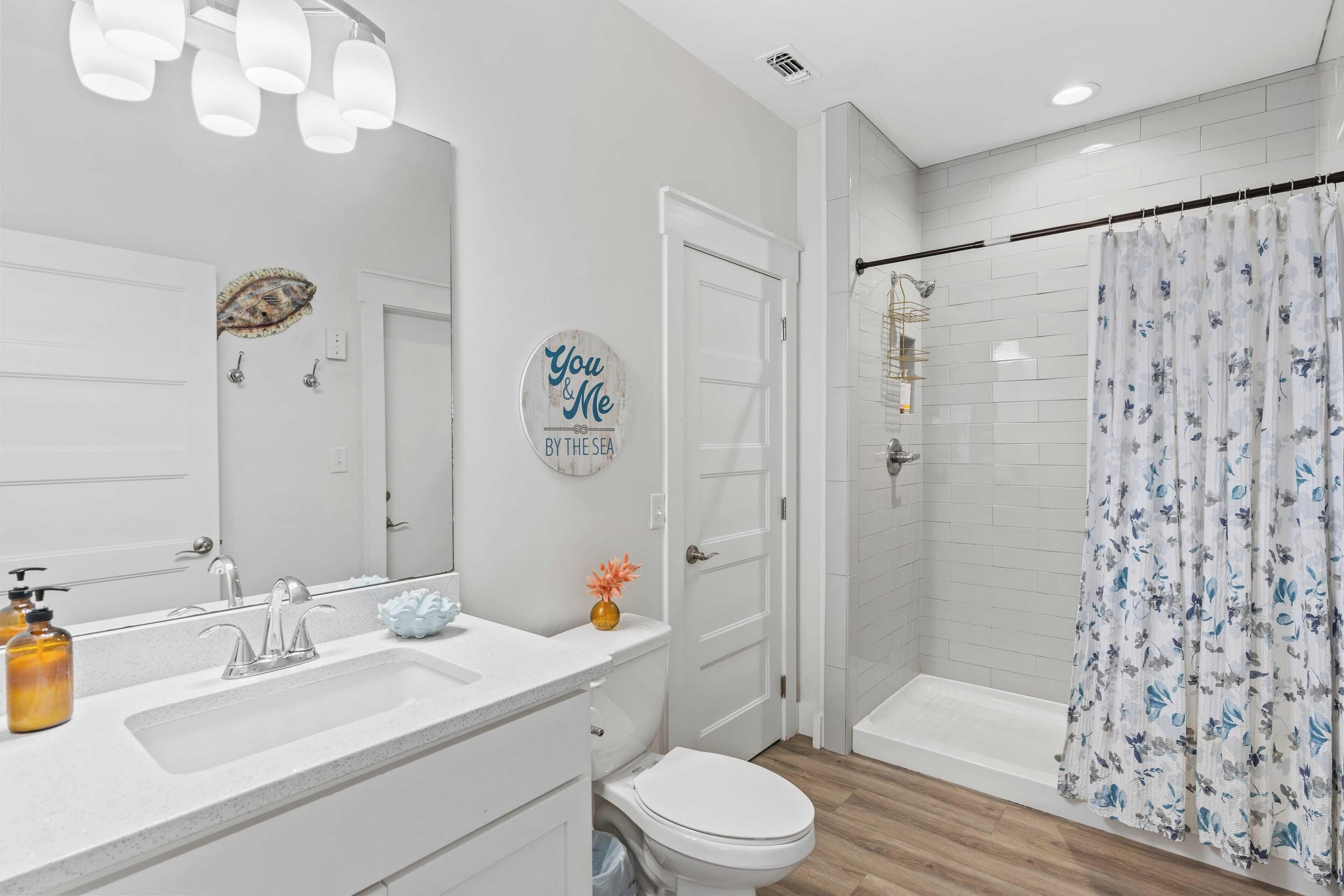 A modern bathroom with a white sink, a toilet, and a shower area.