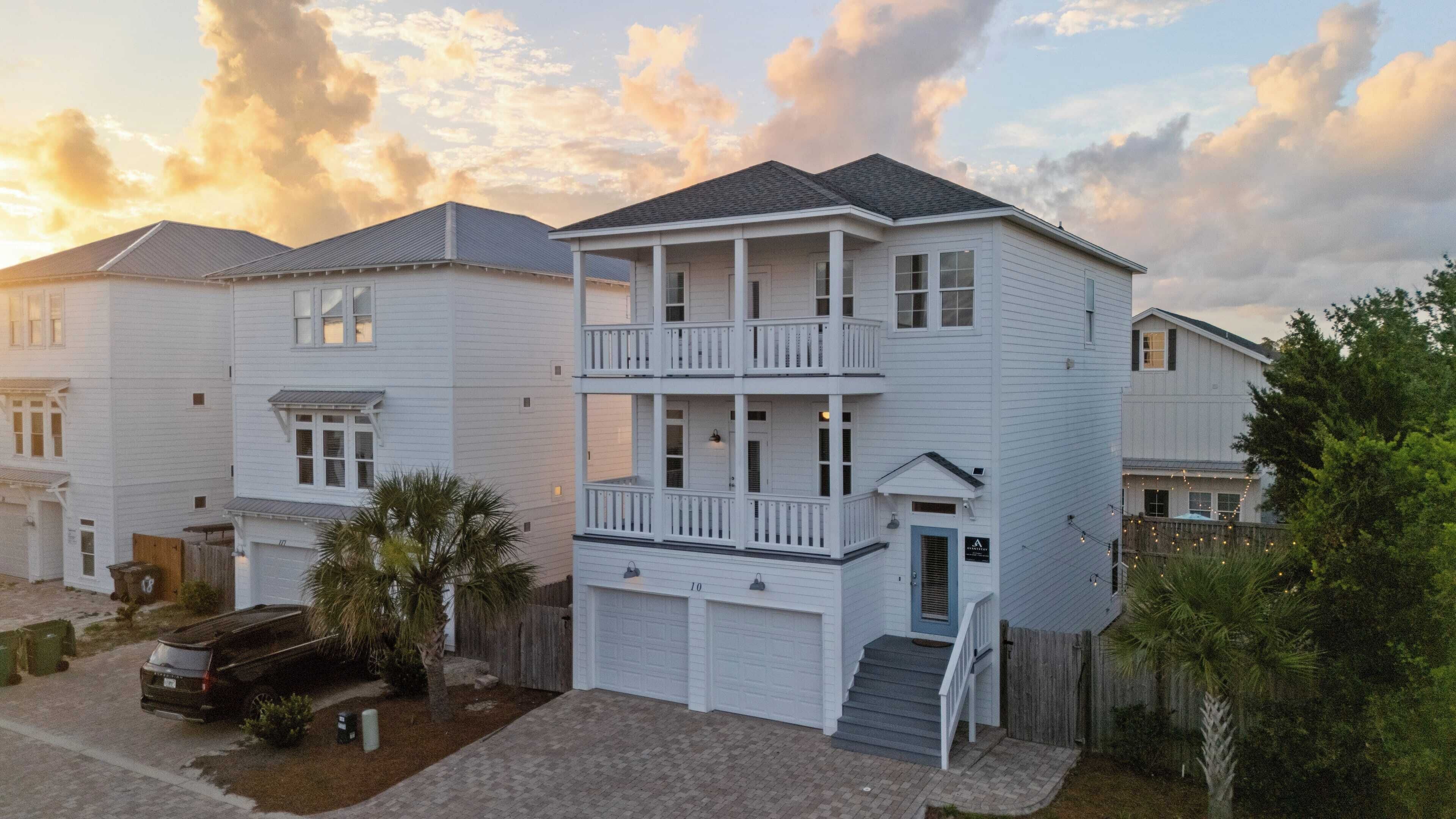 A two-story residential building with a balcony on the second floor, a garage, and a driveway.