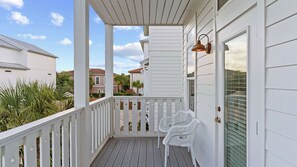 A covered porch with a railing, a door, and a window with blinds. - Pool, Firepit, Near Miramar Beach Access Blue Surf Lane by Avantstay (Miramar Beach)