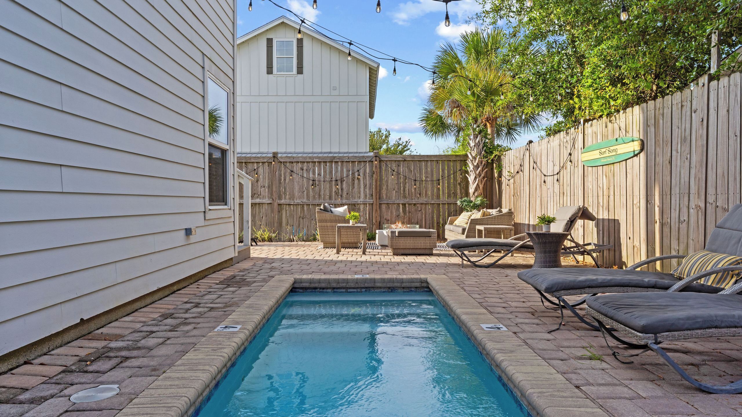 A backyard with a swimming pool, outdoor furniture, and a wooden fence.