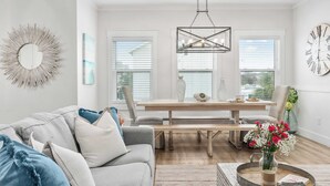 Un salon moderne avec un canapé gris, une table à manger en bois et un lustre.