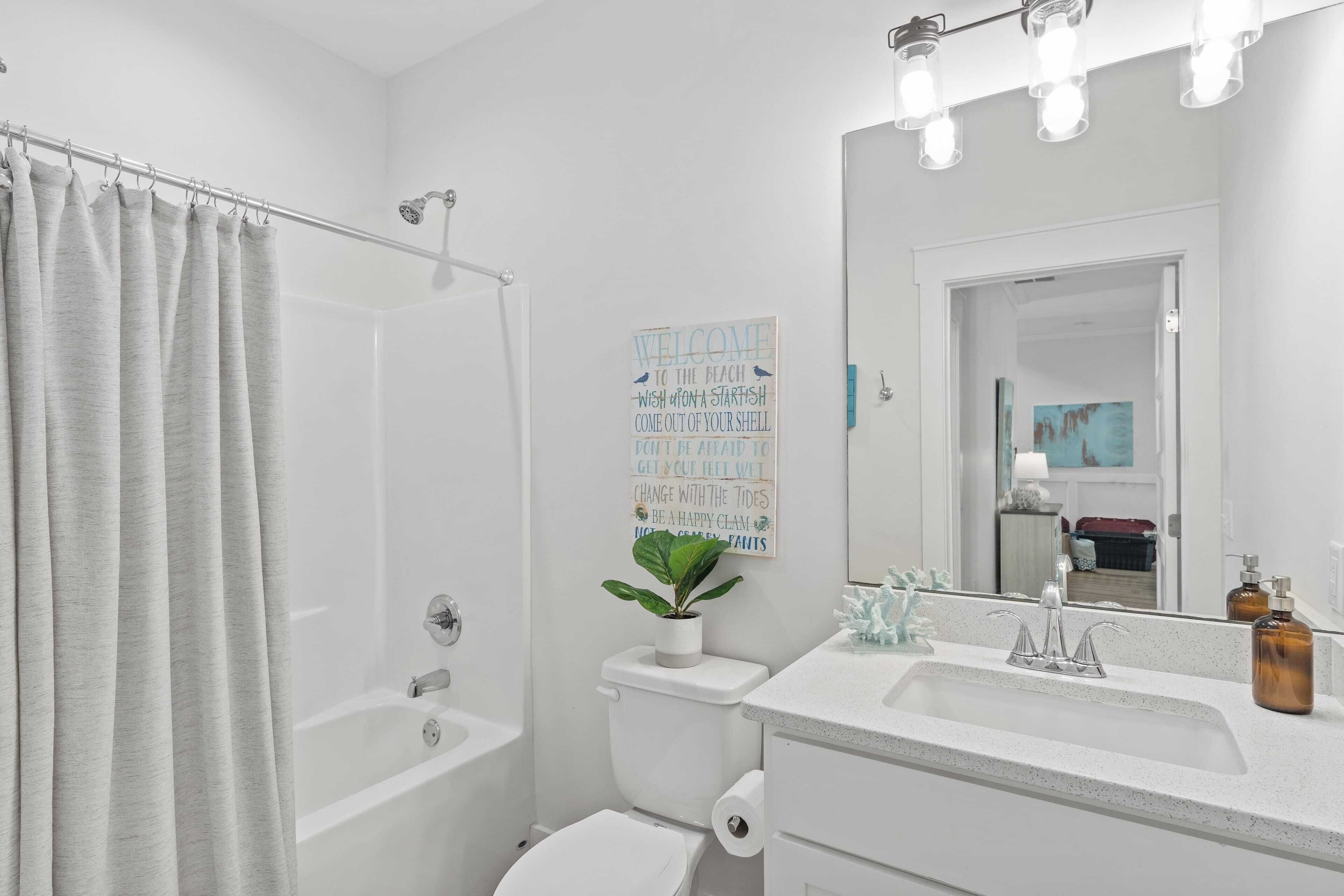 A bathroom with a shower, toilet, sink, and a mirror.