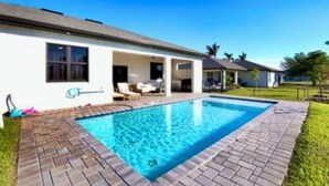 Ein Wohnhaus mit Schwimmbad, überdachter Terrasse und gepflegtem Rasen.
