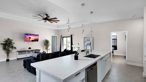 Eine moderne Küche mit einer großen Kochinsel, weißen Schränken und einem Deckenventilator.