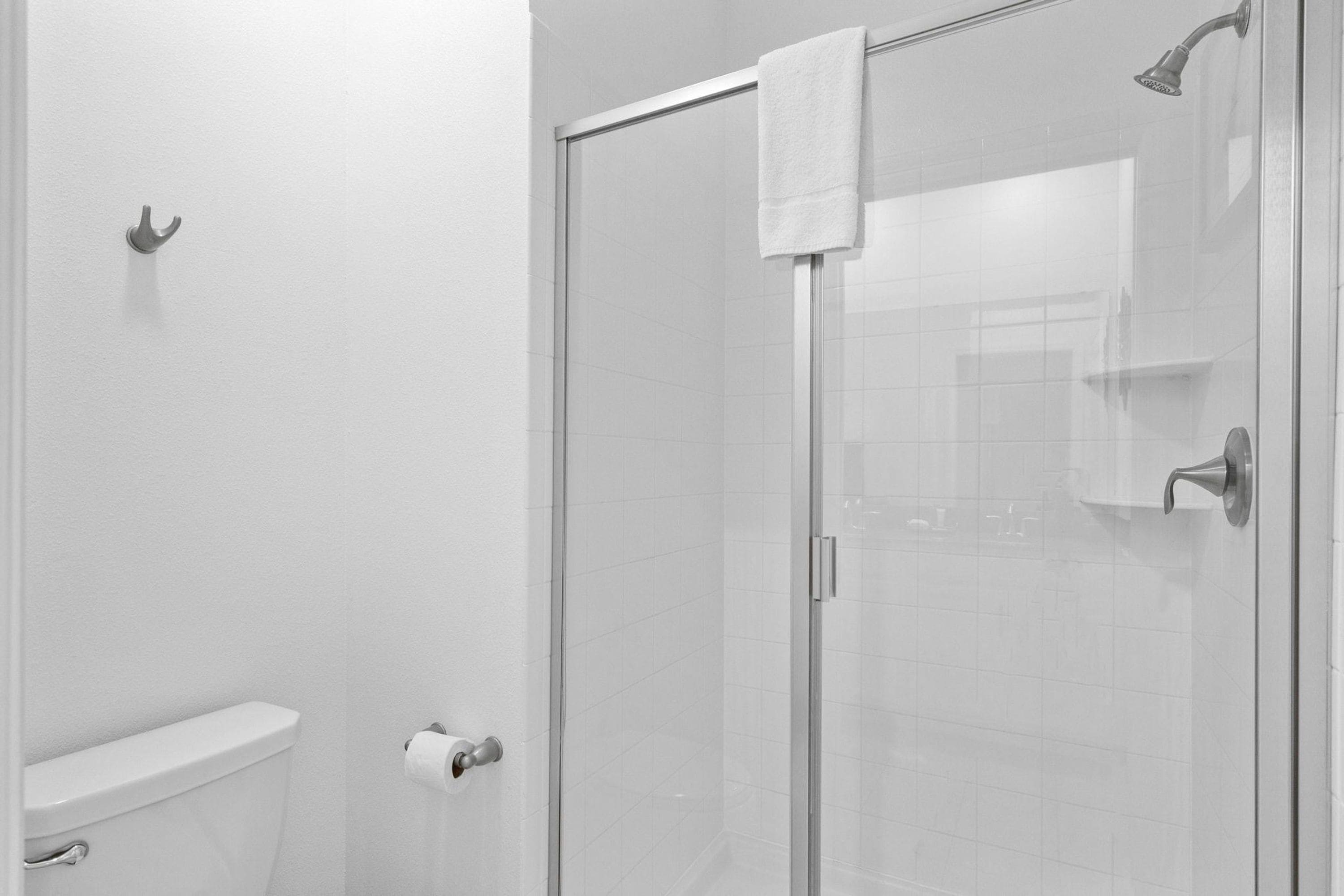Un baño moderno con cabina de ducha de vidrio, inodoro y perchero.