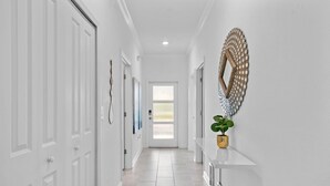 A hallway with white doors, a white console table, and a decorative wall piece. - Spacious 5BR Home With Pool Near Top Attractions (Davenport)