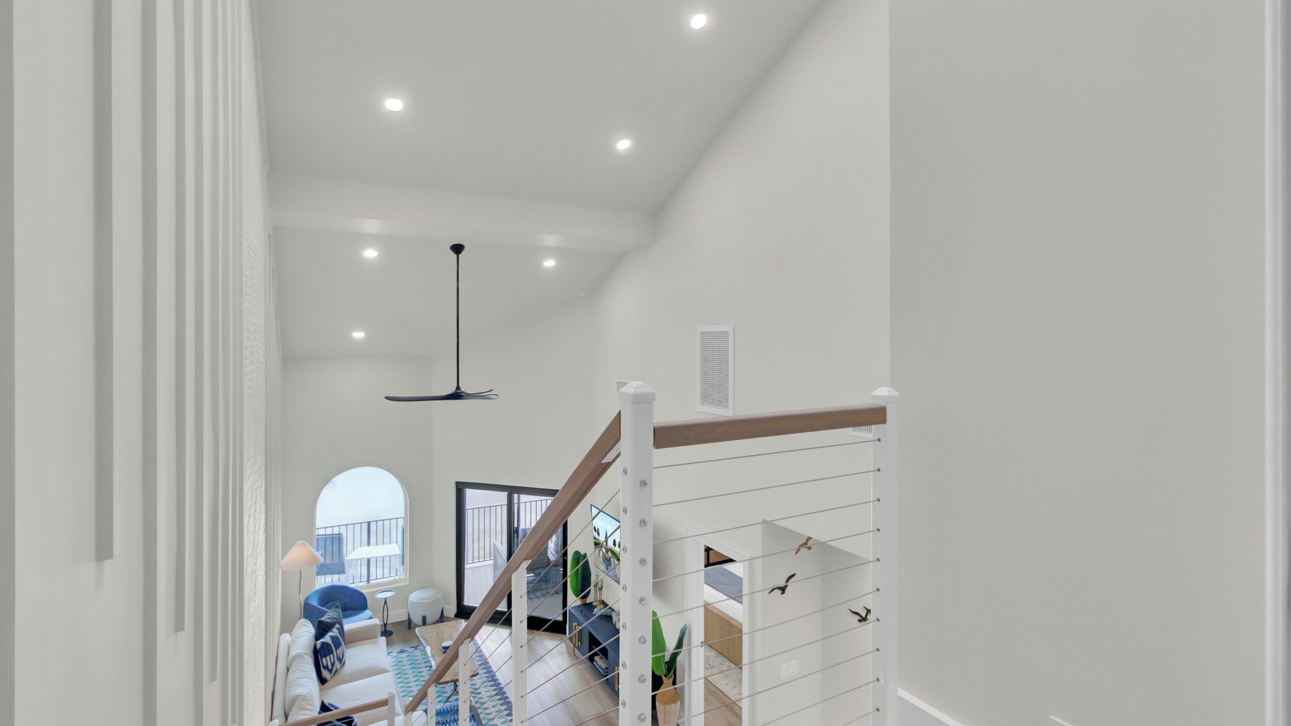 A modern interior with a staircase, a dining area, and a view to the outside.