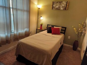 A bedroom with a bed, bedside lamp, and a wall-mounted painting. - Stylish & Convenient 2Bd/1Bth~for Friends/Business/Family~FREE Parking (Atlanta)