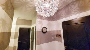 Un corridoio con una lampada decorativa a soffitto, una sveglia e una porta.