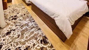Une chambre d’hôtel avec deux lits, une tête de lit en bois, un grand miroir et un tapis en peau de vache.