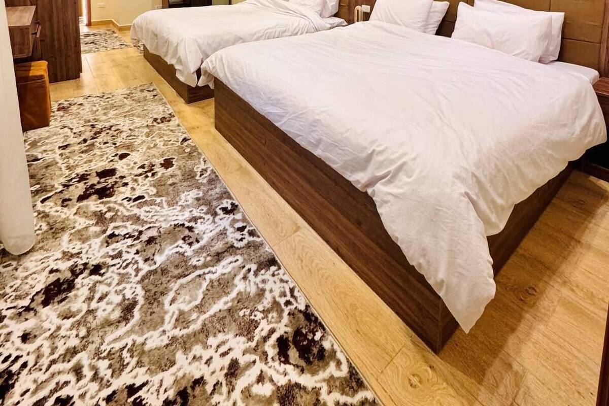 A hotel room with two beds, a wooden headboard, a large mirror, and a cowhide rug.