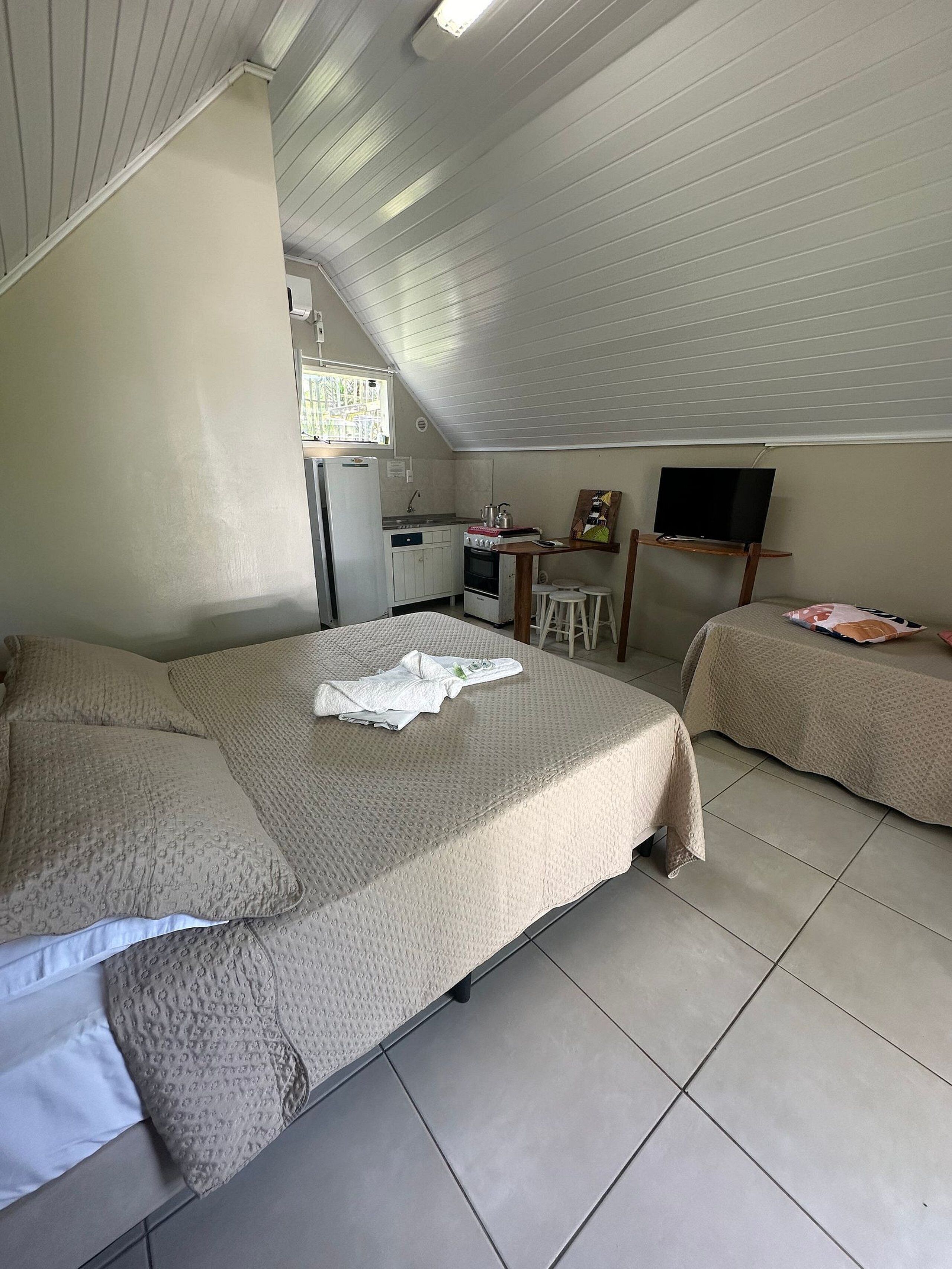 Une pièce de taille modeste comprenant un lit, une petite kitchenette et un téléviseur.