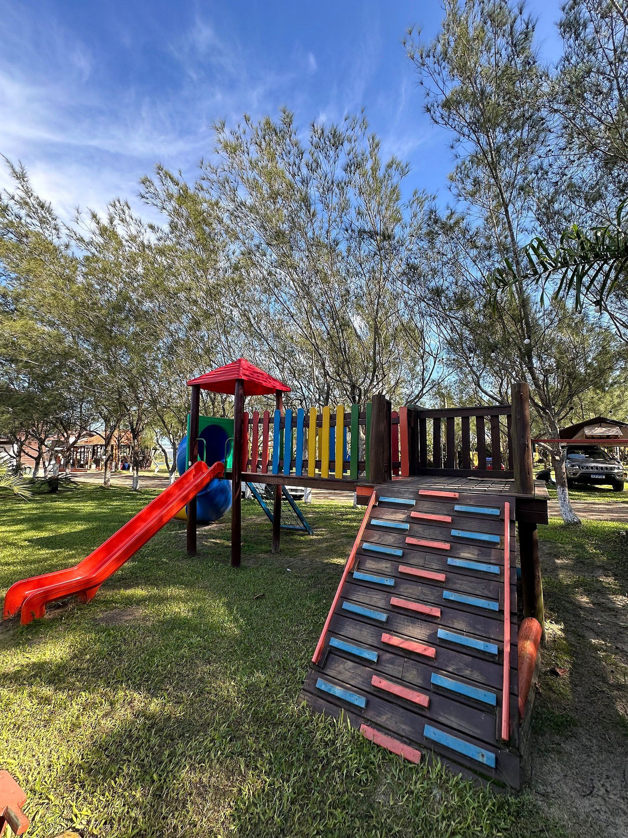 Ein Spielplatz mit Rutsche, Klettergerüst und einer Holzrampe.