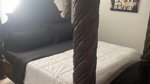Un llit amb cortines i un estovat blanc, una frase motivadora a la paret i una catifa amb dibuixos.