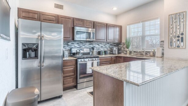 A modern kitchen with stainless steel appliances, wooden cabinets, and a granite countertop. - Carson Flats Apt #6 | 1BR • Near BOK• OSU Med•Dtwn (Tulsa)