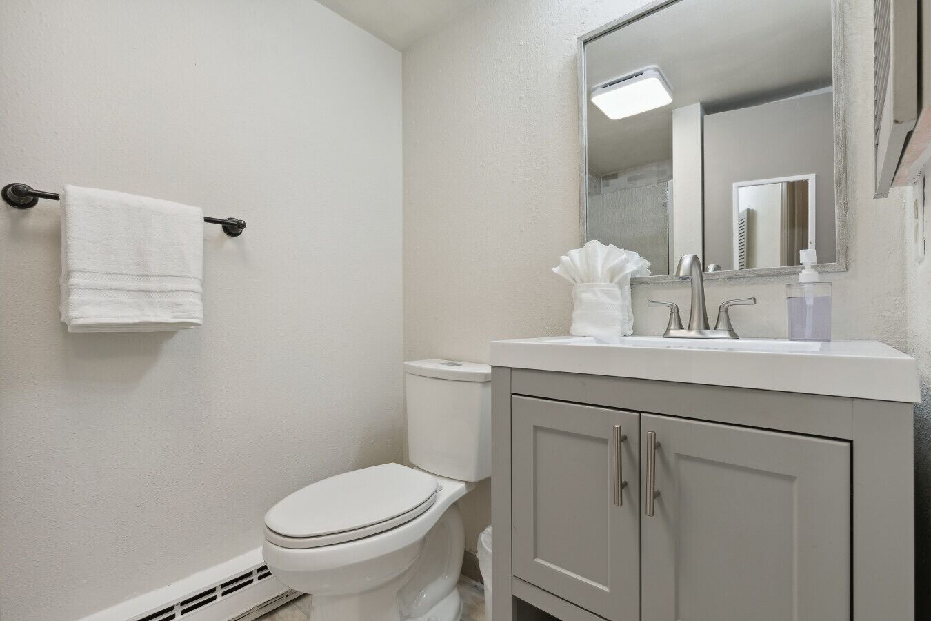 Een badkamer met toilet, wastafel en spiegel.