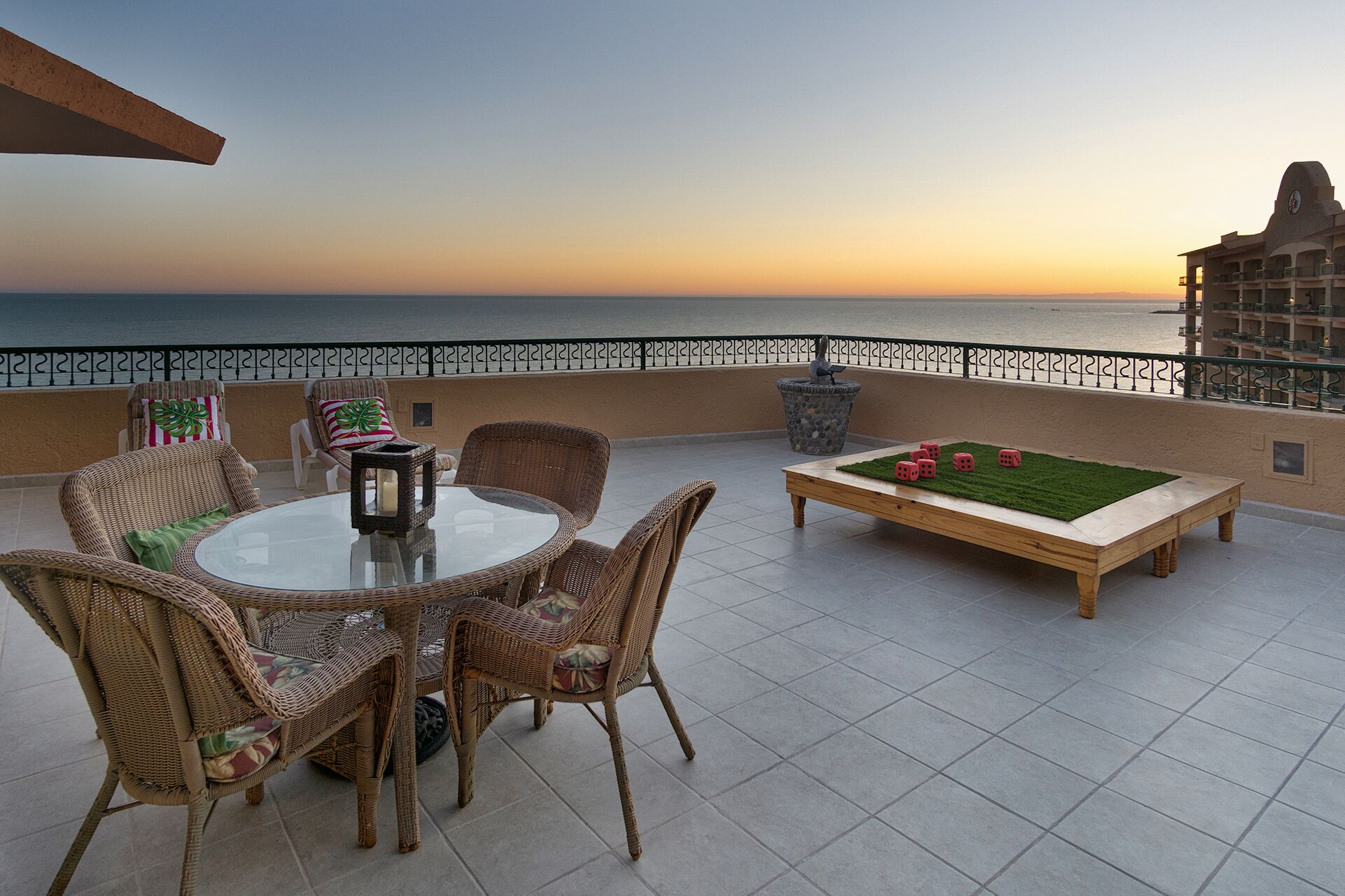 Um terraço com móveis de vime, uma mesa e um jogo de tabuleiro.