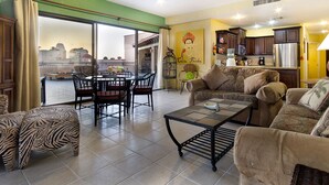 A spacious living room with a dining area, a kitchen, and a balcony with a view of buildings. - Casa Frida Massive Condo Sleeps up to 12! (Puerto Peñasco)