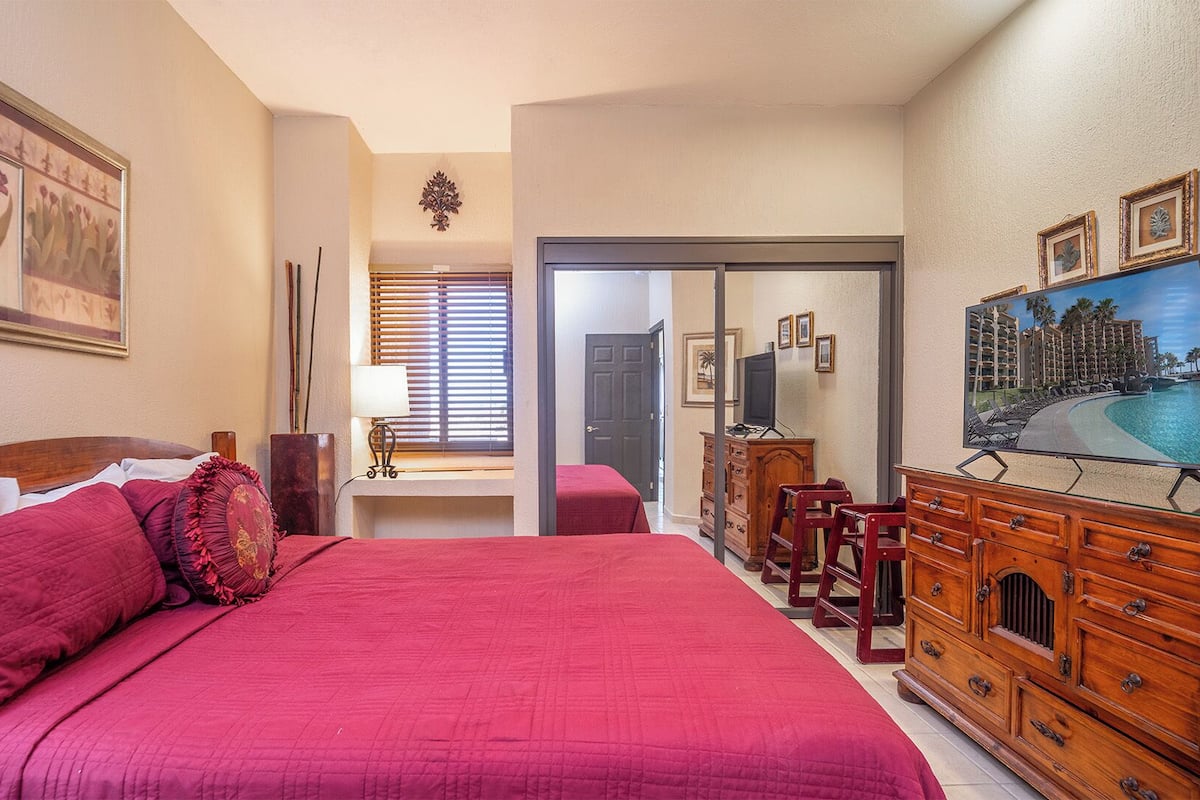 Une chambre d’hôtel avec un grand lit, un bureau, une télévision et une vue sur la piscine.