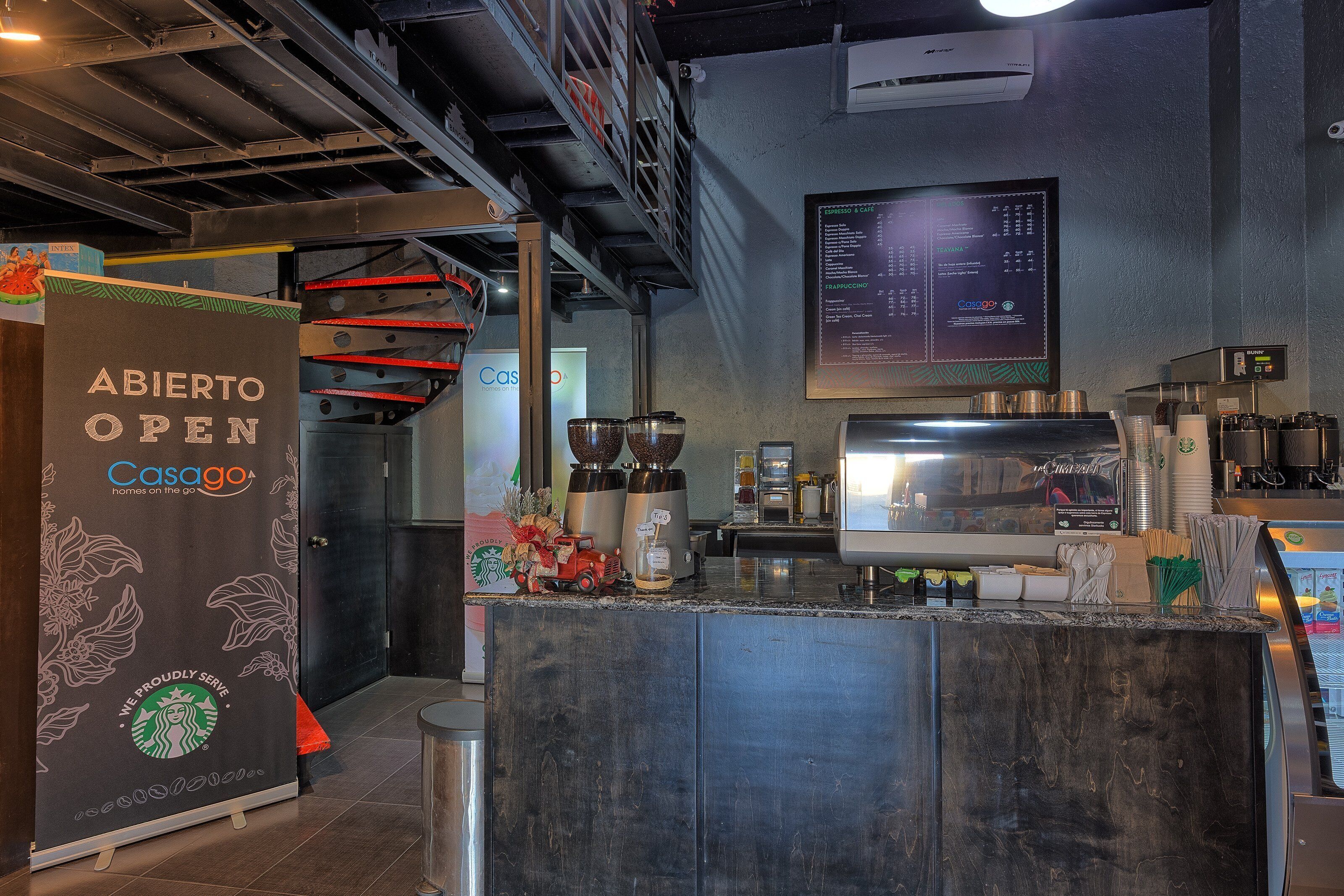 Een modern koffiehuis interieur met een barista station, espresso machines en een menubord.