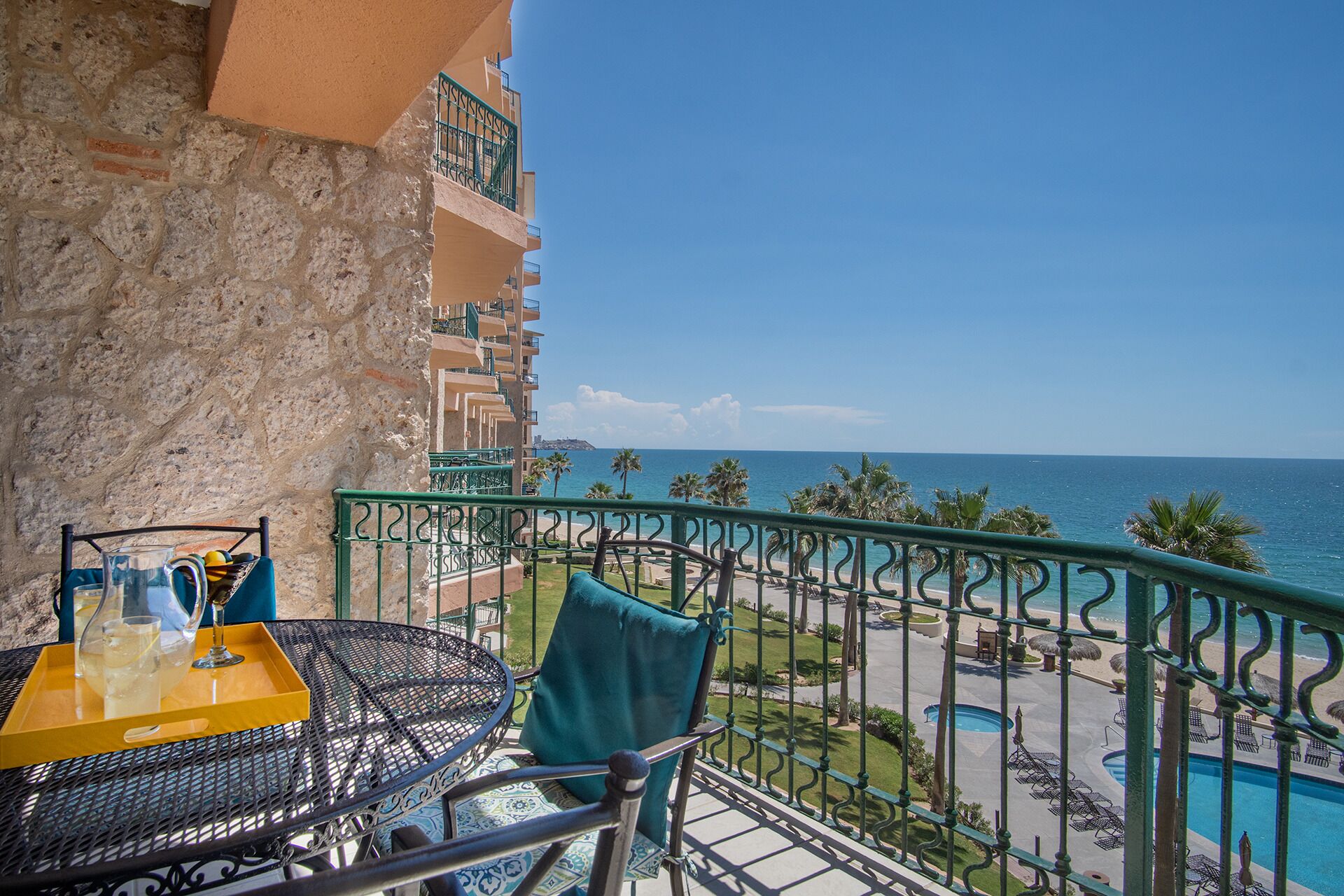 A balcony with a table, chairs, and a view of the ocean.