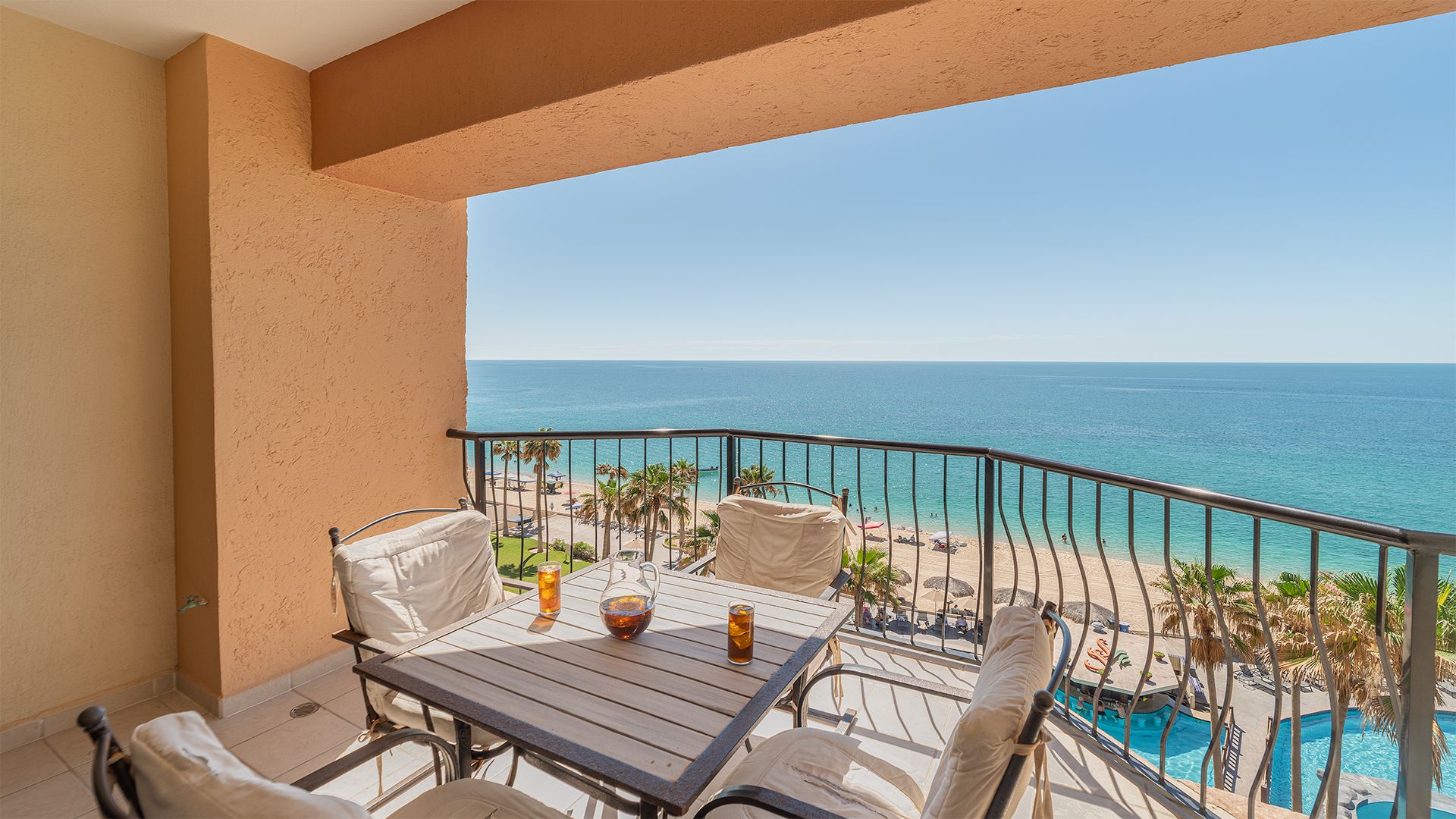Un balcon avec une table, des chaises et une vue sur l’océan et la plage.