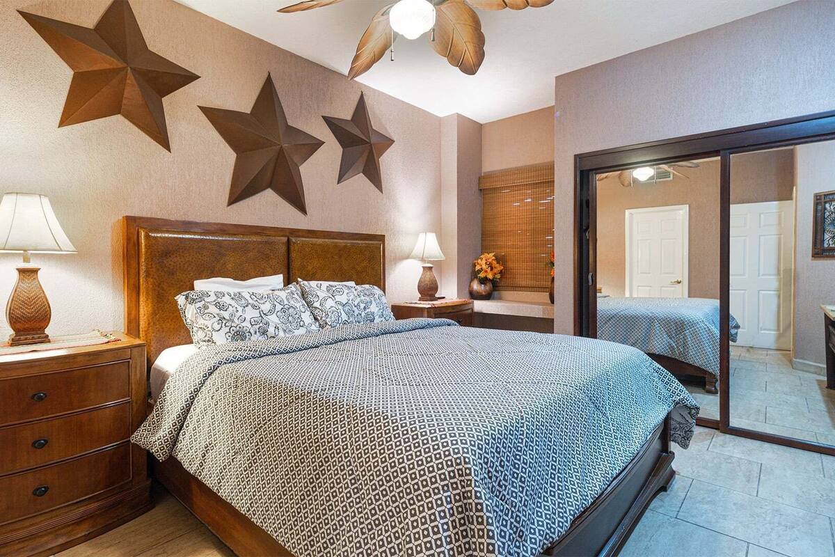 Een slaapkamer met een houten bed, twee nachtkastjes met lampen, een grote spiegel en decoratieve sterren aan de muur.