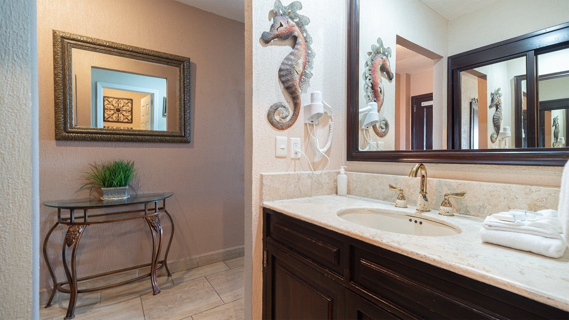A bathroom with a vanity, a mirror, a seahorse decoration, and a potted plant.