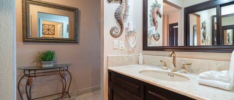 A bathroom with a vanity, a mirror, a seahorse decoration, and a potted plant.