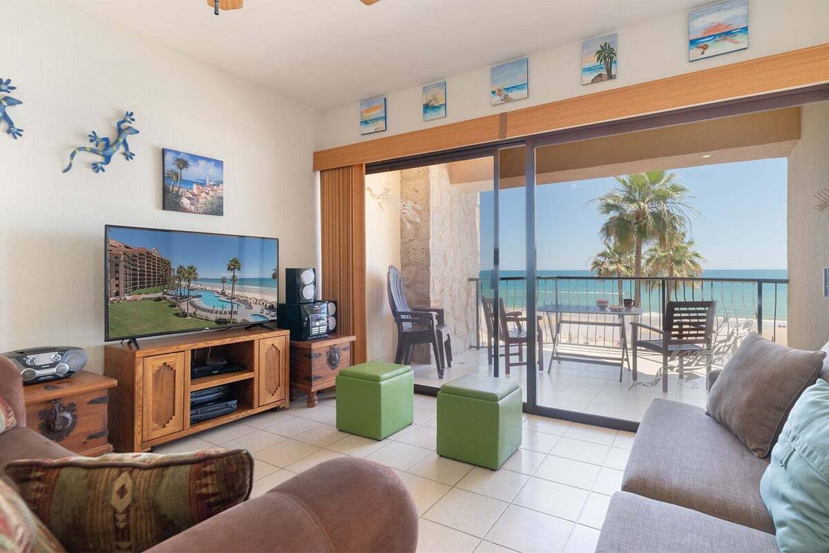 Un salon équipé d’un téléviseur, d’enceintes et offrant une vue sur la plage.