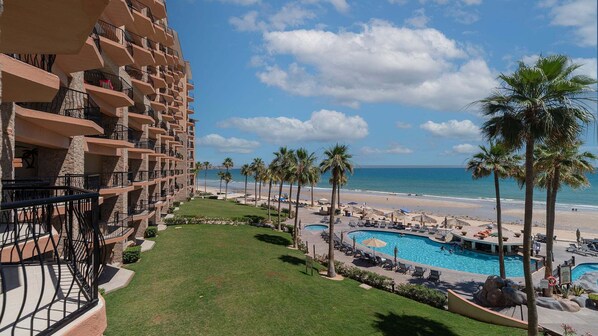 A hotel with a pool, beach, and ocean view.