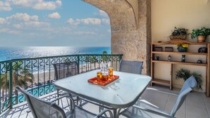 Un balcón con mesa y sillas, con vista a una playa y al mar.