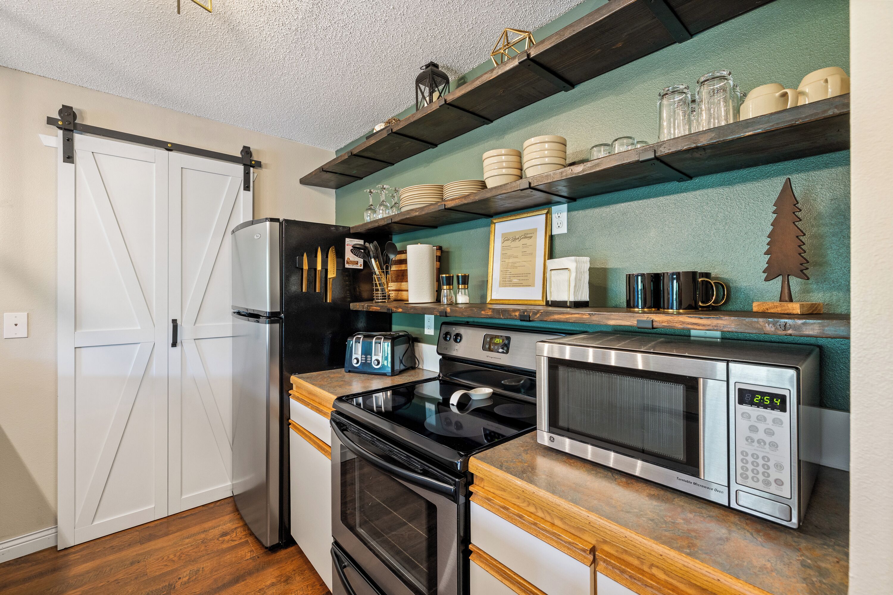 A kitchen with a refrigerator, stove, microwave, and wooden countertop.