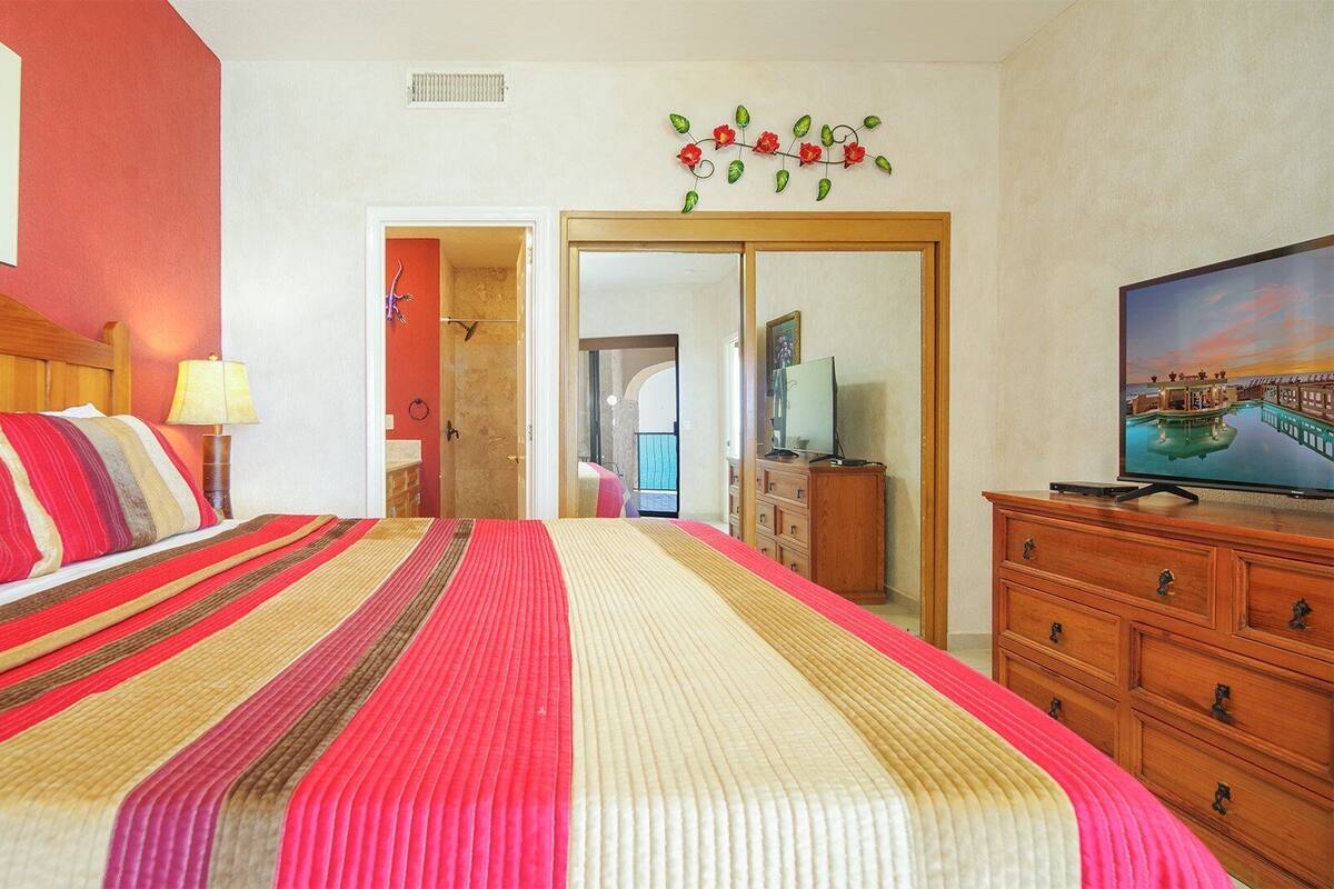 Een hotelkamer met een groot bed, een houten dressoir, een televisie en een schilderij aan de muur.