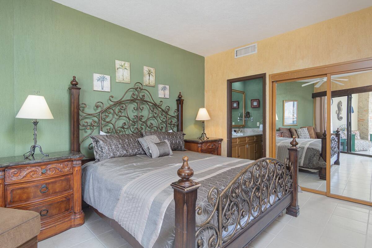 Een slaapkamer met een groot bed, twee nachtkastjes, een spiegel en kunstwerken aan de muren.
