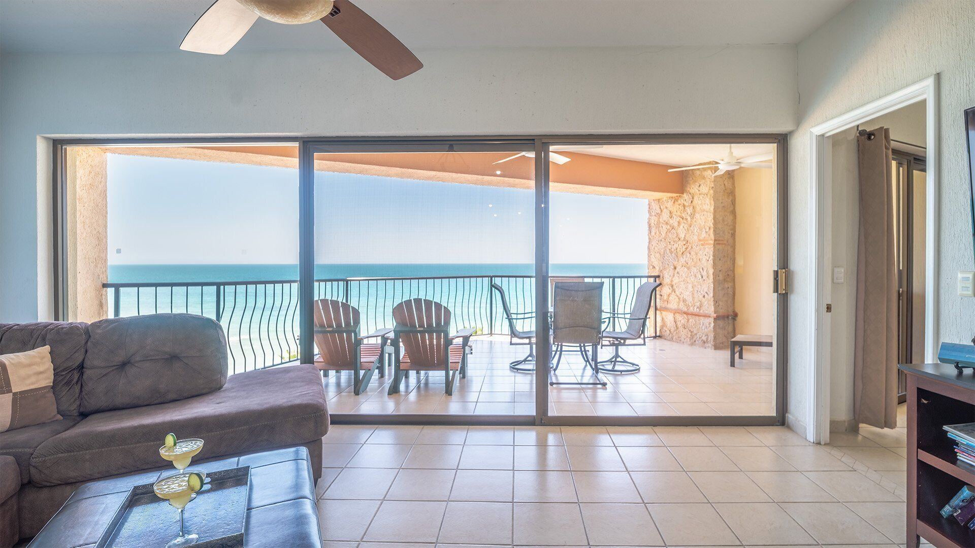 A balcony with a view of the ocean, furnished with chairs and a table.