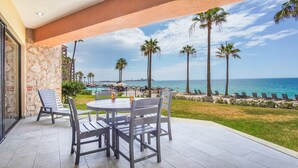 Eine Terrasse mit Tisch und Stühlen mit Blick auf Pool und Strand.