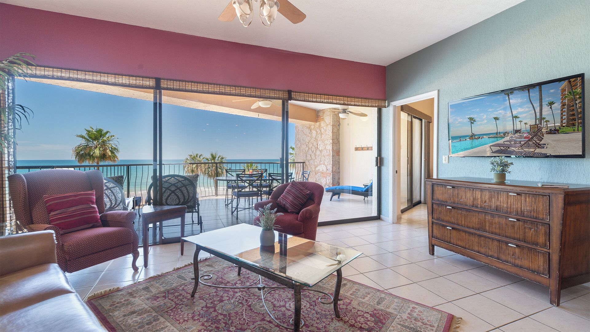 Een ruime woonkamer met een glazen deur die leidt naar een balkon met uitzicht op de oceaan.