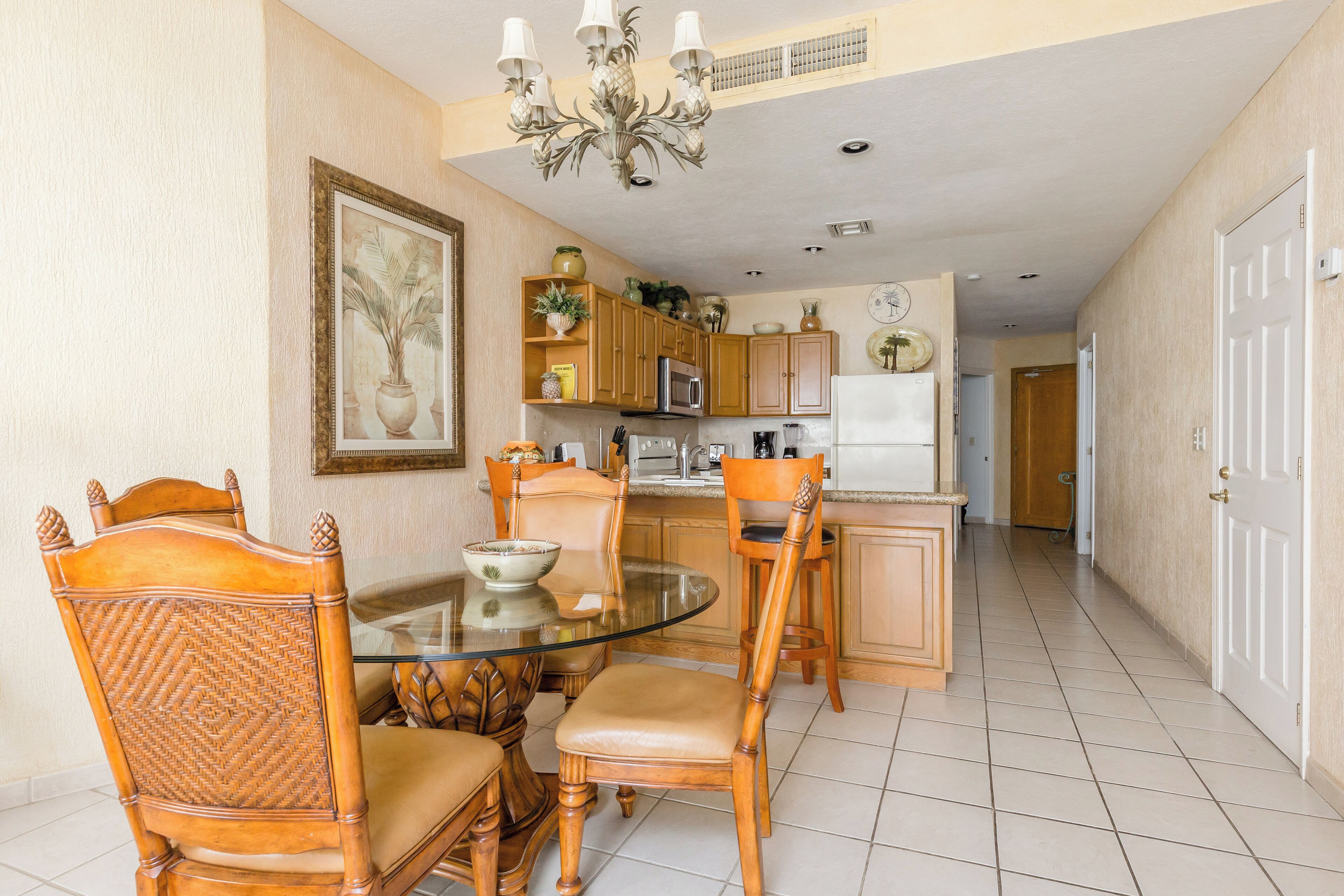 Zona pranzo con tavolo in vetro, sedie di legno e lampadario.