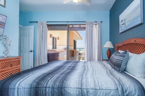 Ein Schlafzimmer mit Bett, Nachttisch, Lampe und Blick auf Balkon und Außenbereich.