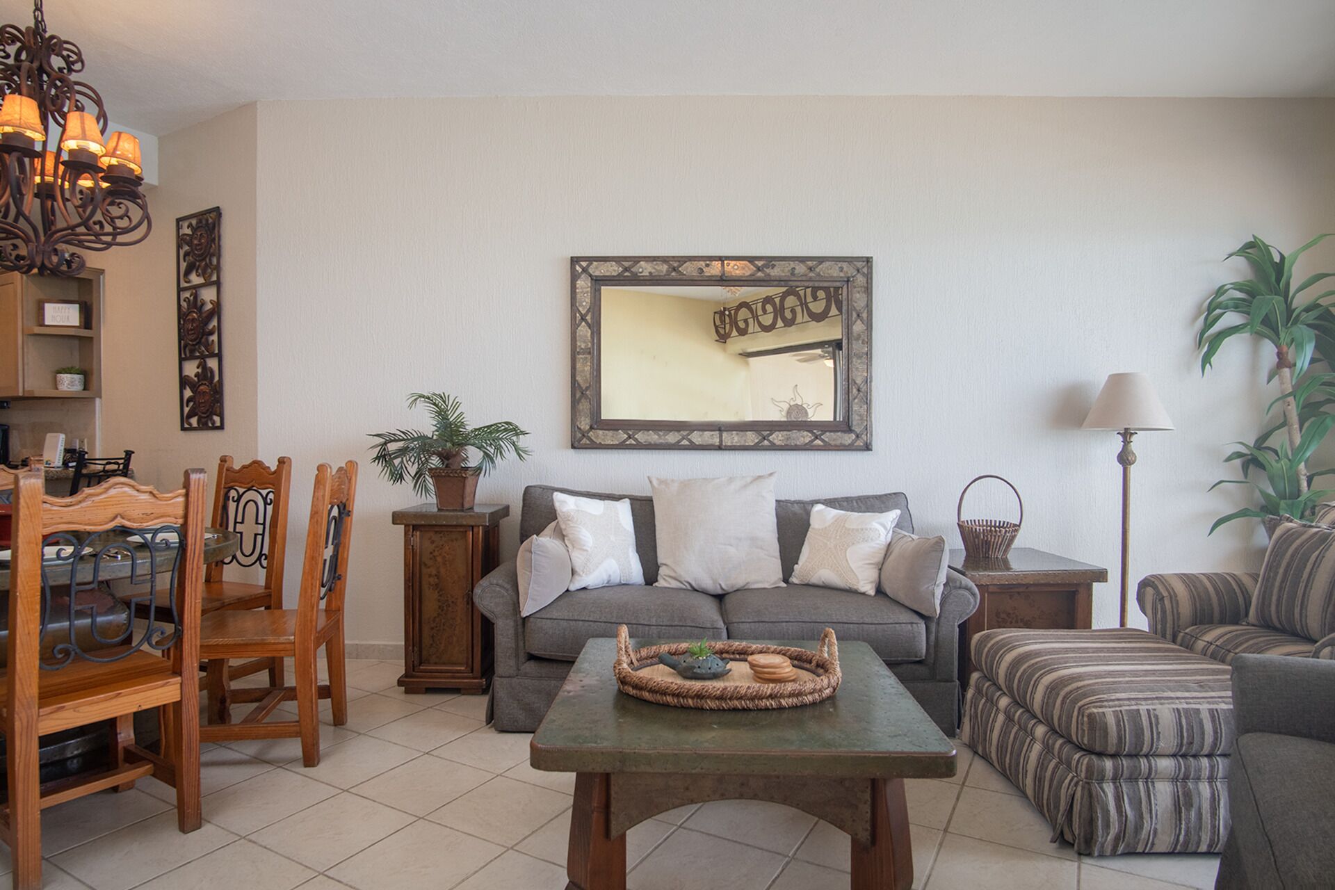 Un salon comprenant un canapé, une table basse, une table à manger avec des chaises, une plante en pot et un lampadaire.
