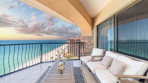 A balcony with a view of the ocean and a hotel building in the background.