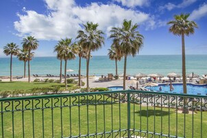A pool area with palm trees and a view of the ocean.