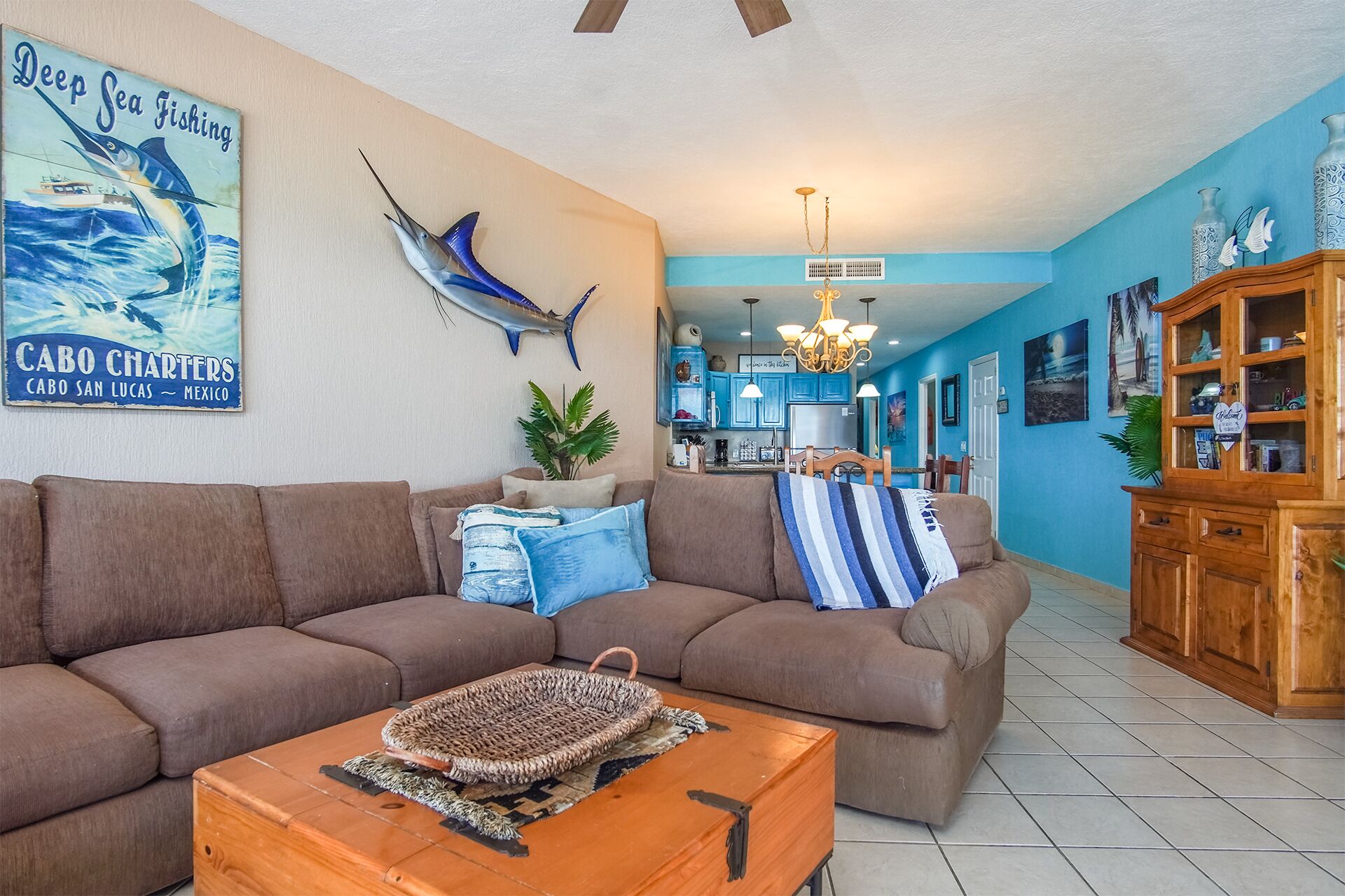 A living room with a large brown sofa, a coffee table, and a wall-mounted fish sculpture.