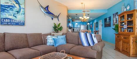 A living room with a large brown sofa, a coffee table, and a wall-mounted fish sculpture.