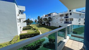A modern apartment complex with balconies, a well-maintained lawn, and a view of the sea.