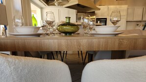 A dining table set with wine glasses and bowls, flanked by white chairs. - Minimalist Lake House (Helendale)