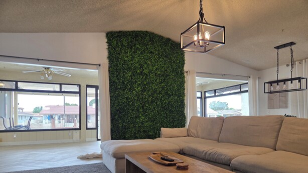 A modern living room with a large green wall, a beige sofa, and a wooden coffee table. - Minimalist Lake House (Helendale)